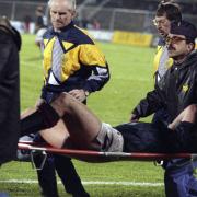 Scotland striker Ally McCoist is removed from the field on a stretcher after suffering a serious injury.